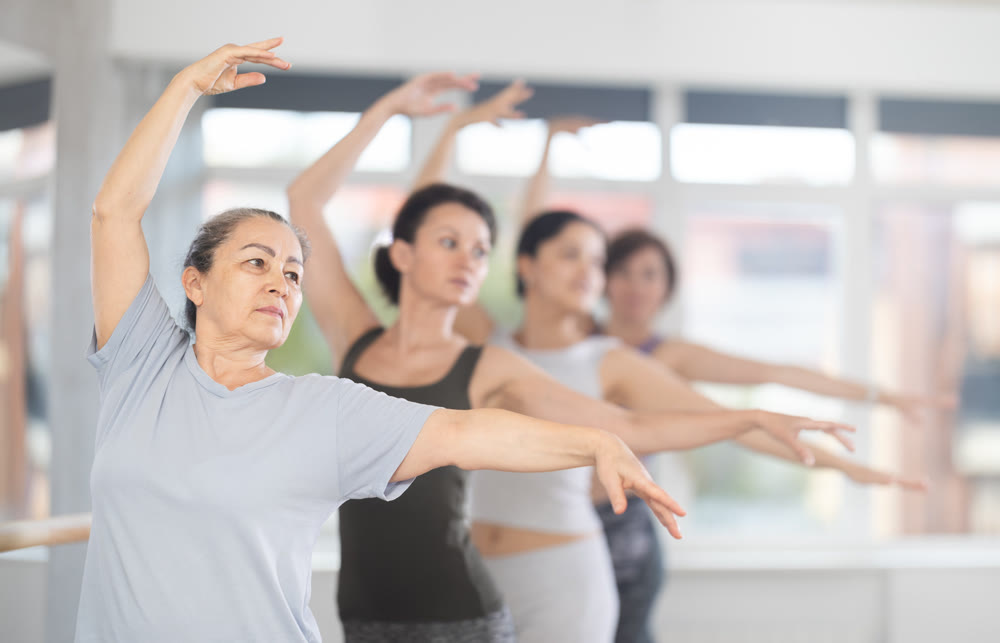 Group of women beginners practicing at ballet barre