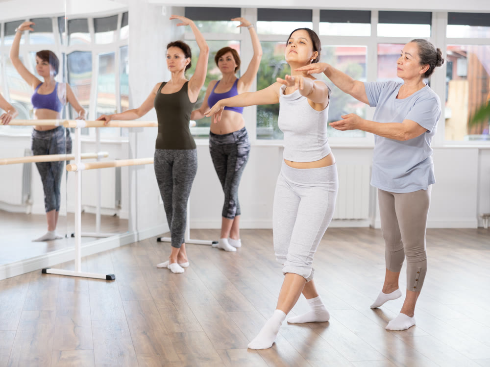 Elderly woman teacher correcting female dancers
