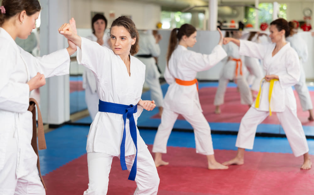 Women pupils train to perform defensive karate installations and attacking combat techniques