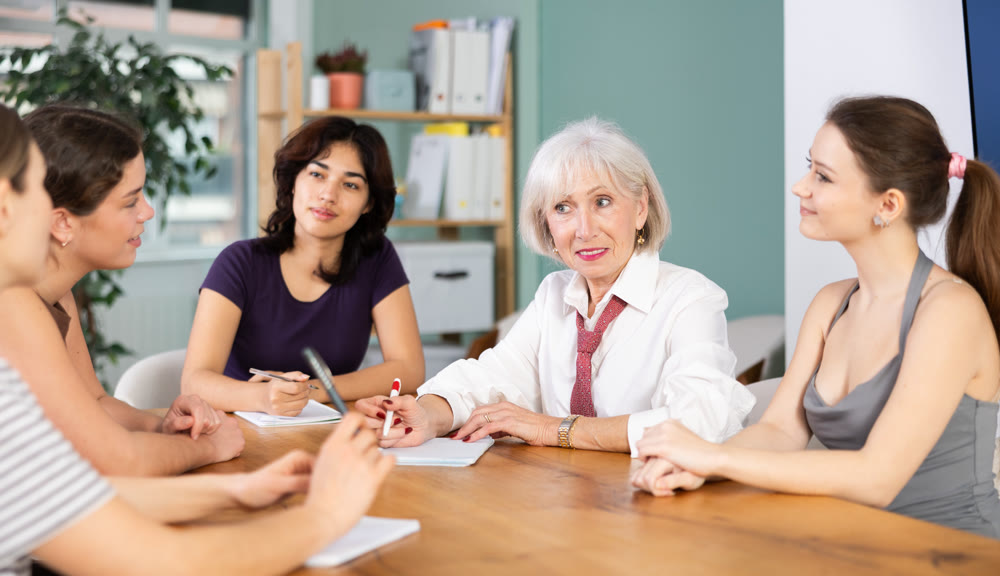 Interested office female workers sitting at table with papers and discussing ideas during business meeting in office