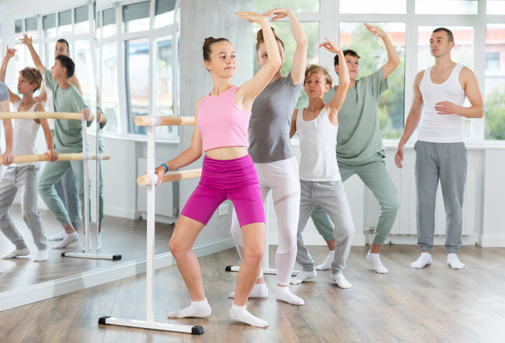 Ballet lesson for teenagers - choreographer teaches girls and boys ballet steps in studio