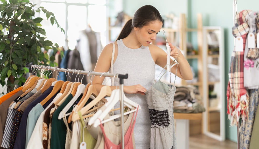 Young woman choosing dress in clothing store