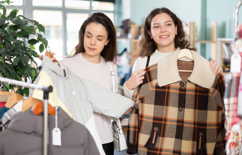 Female friends standing in the store and choosing outerwear