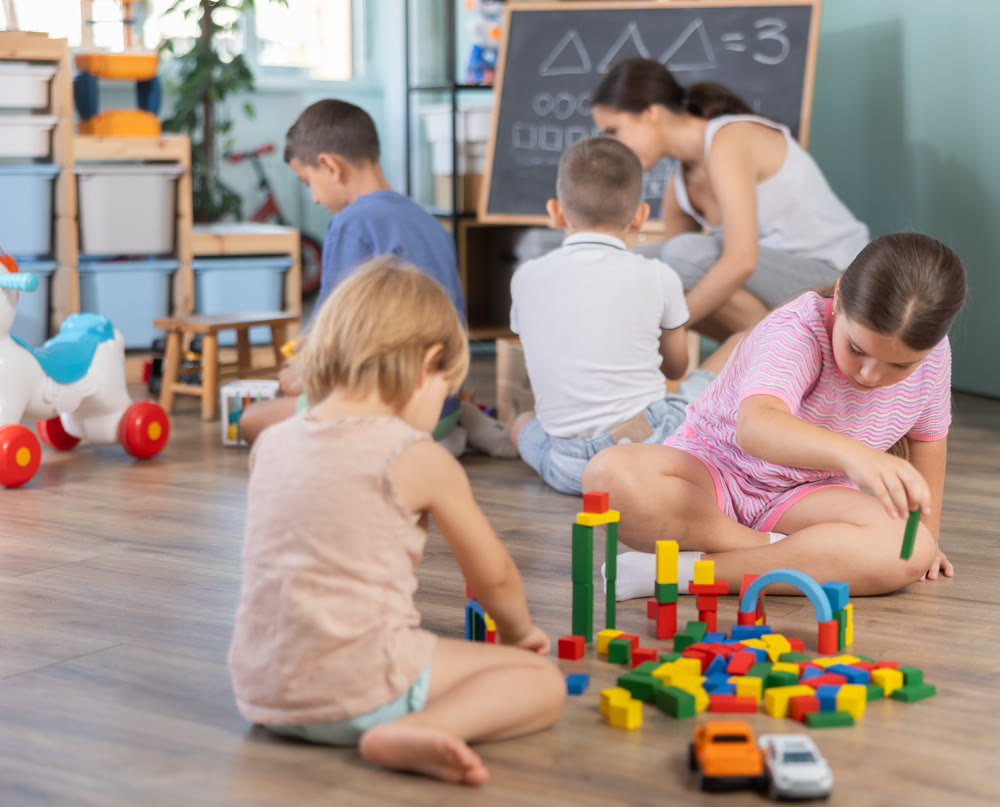 Team of kids playing educational games sitting on floor at daycare, summer vacation activity