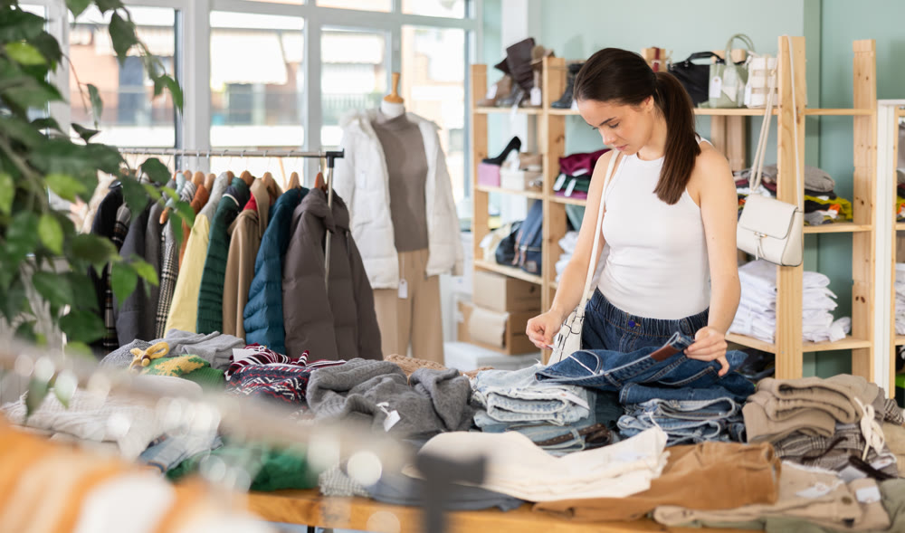 Young woman choosing jeans in clothing store