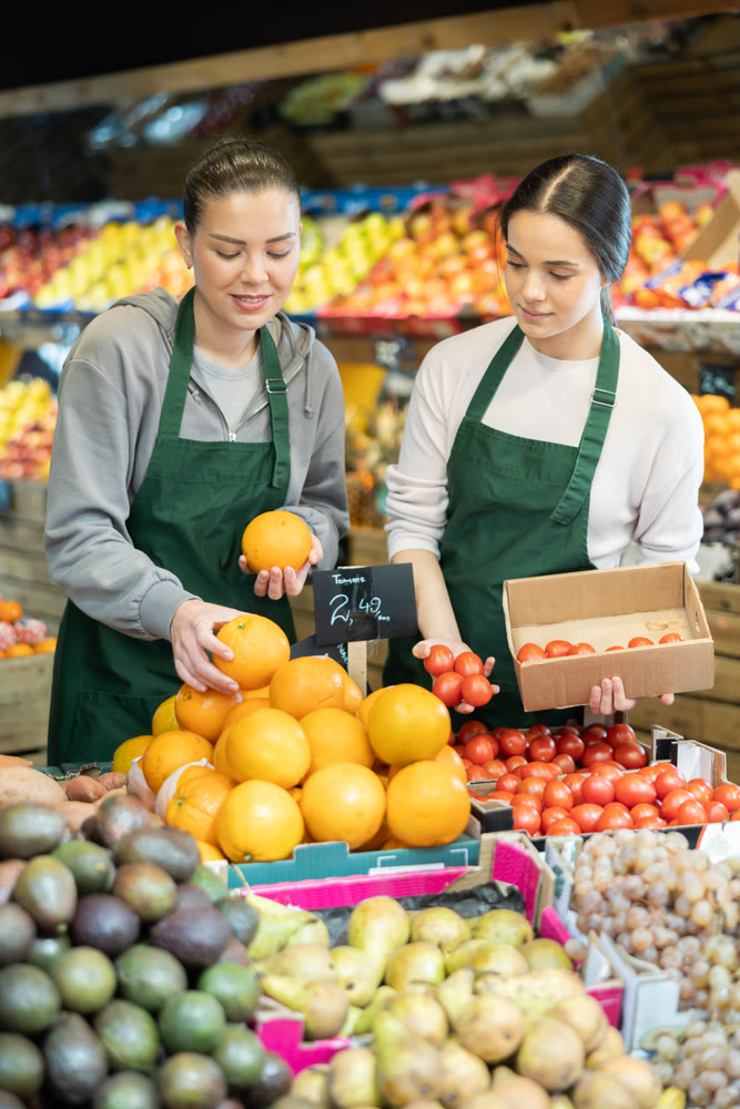 Owners of the grocery store hold ripe fruit in their hands