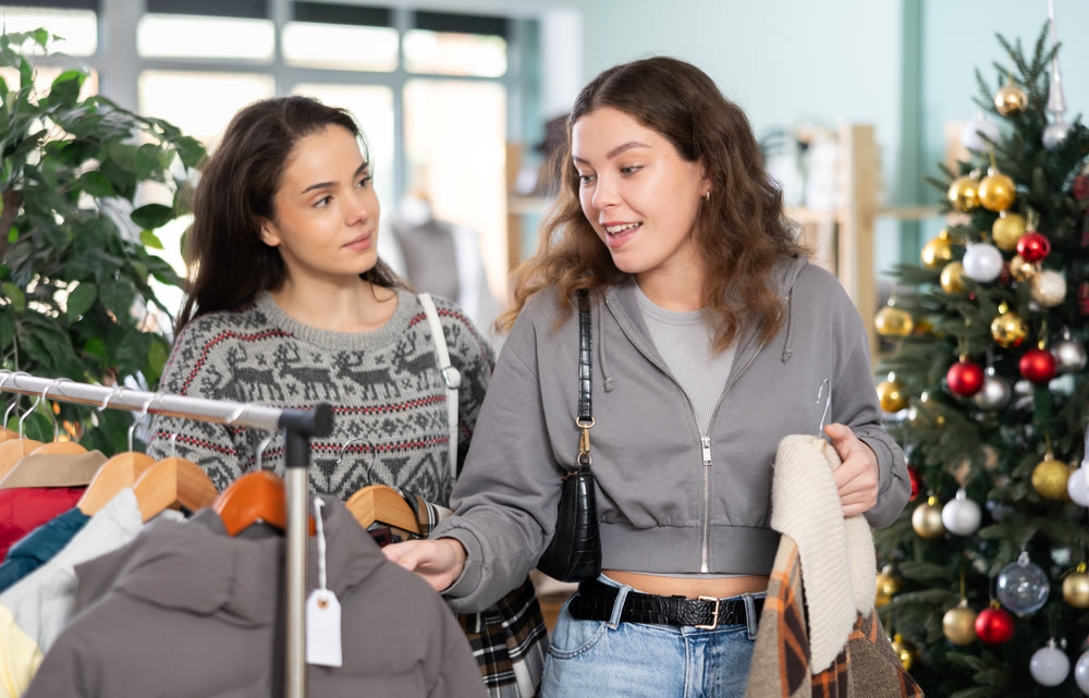Young girls choosing coat or jacket in clothing store during Christmas