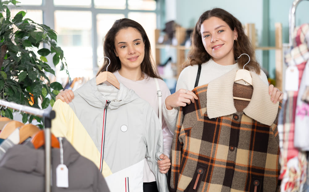 Female friends standing in the store and choosing outerwear
