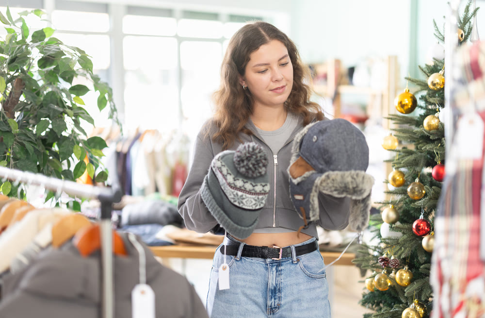 Young woman choosing hat in clothing store