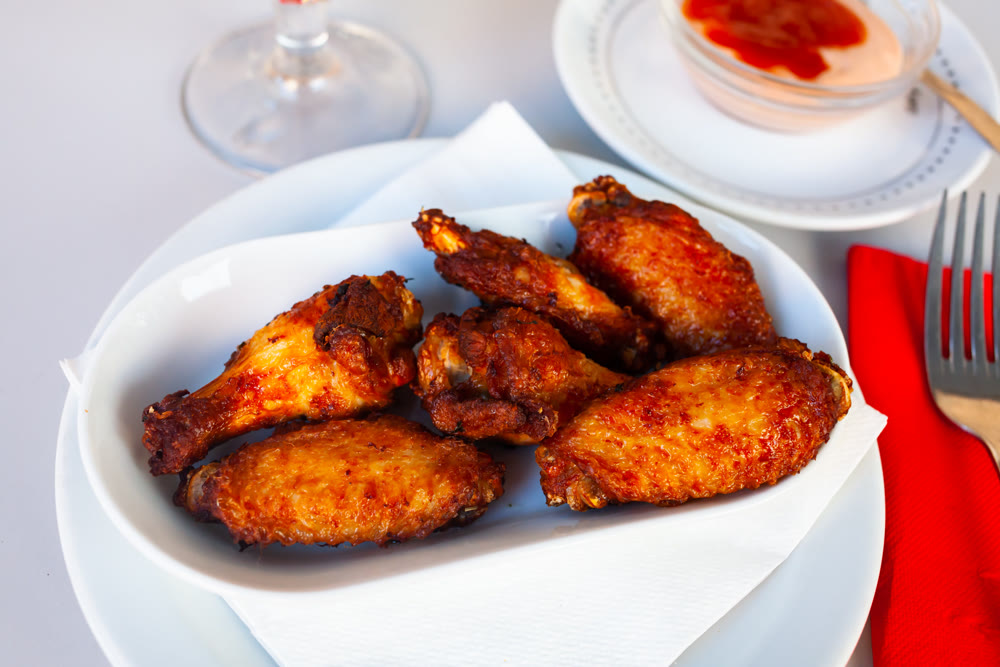Appetizing baked chicken wings in plate closeup