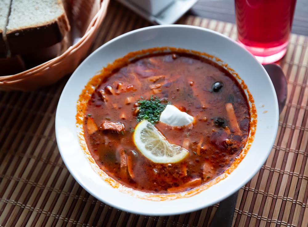 Traditional Russian meat soup Solyanka with sour cream and lemon
