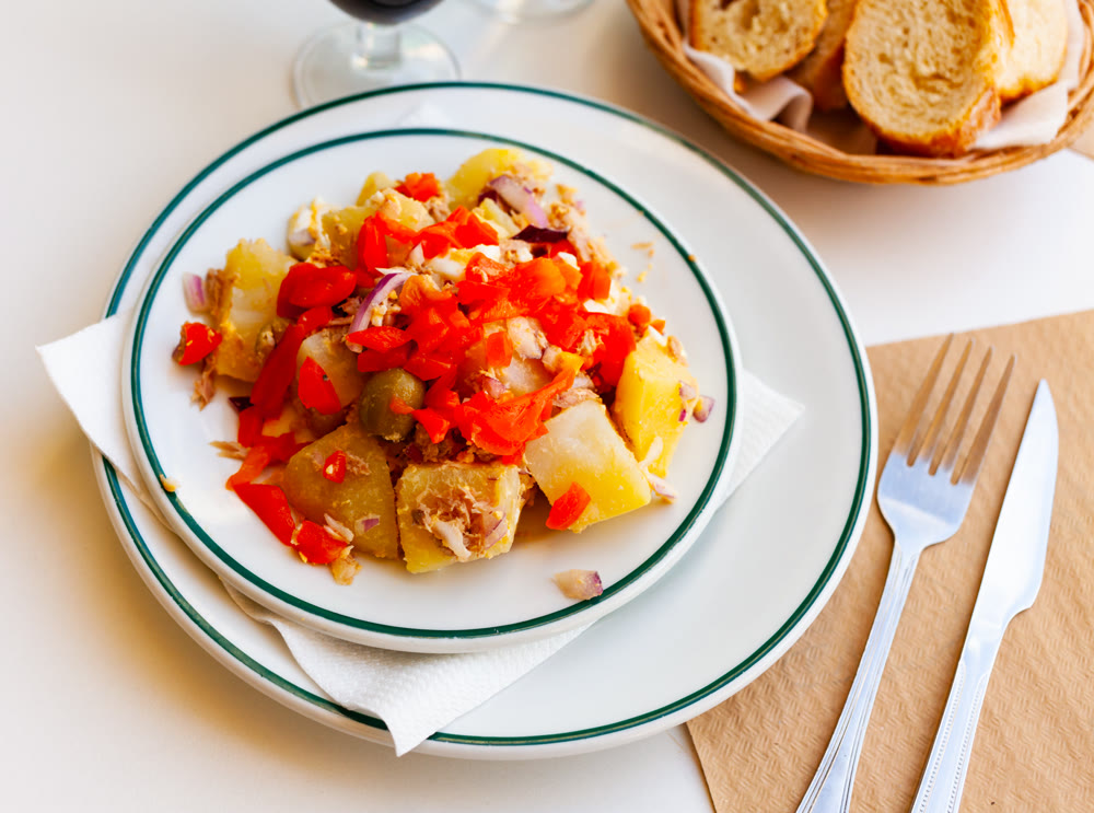 cusine catalan salad with potato and fish in white plate for dinner