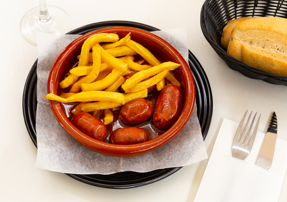 Tasty mini chorizo with cider and french fries, popular Spanish dish Chorizo al sidra