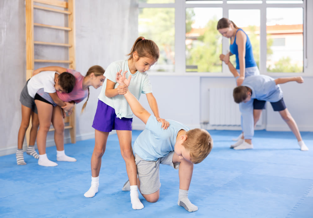 Kids in sportswear exercising self-protection techniques in pair during class