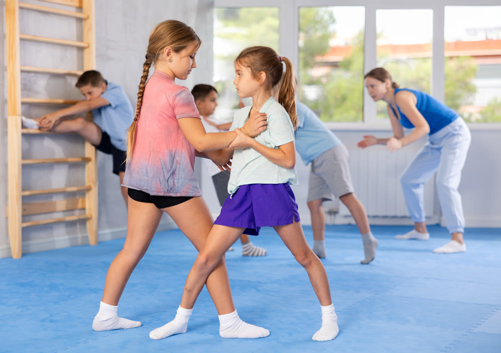 Children, boy and girl, working in pair mastering new self-defense moves at gym