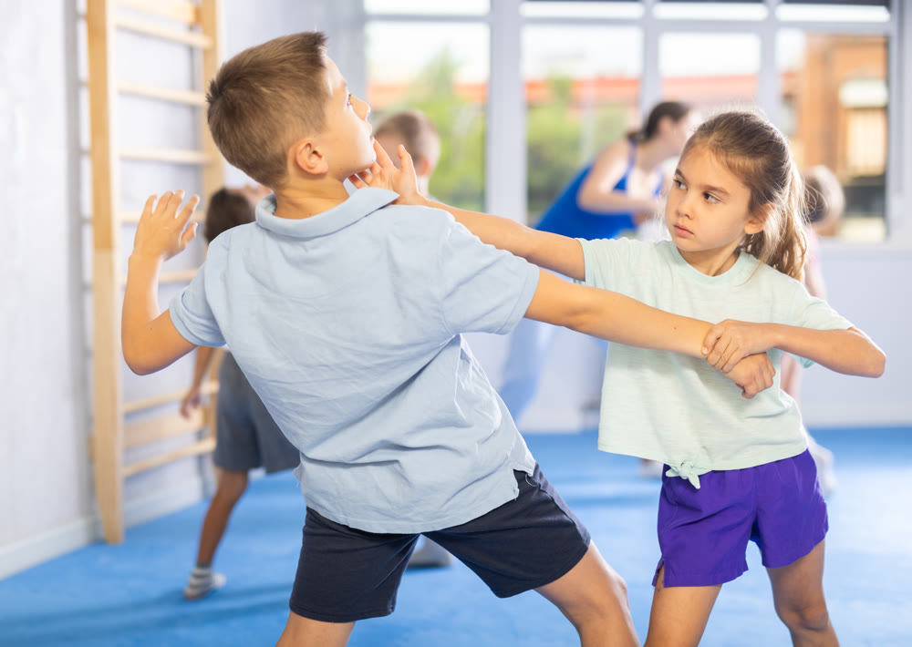 Boys and girls in gym perform basic elements of krav maga self-defense system.