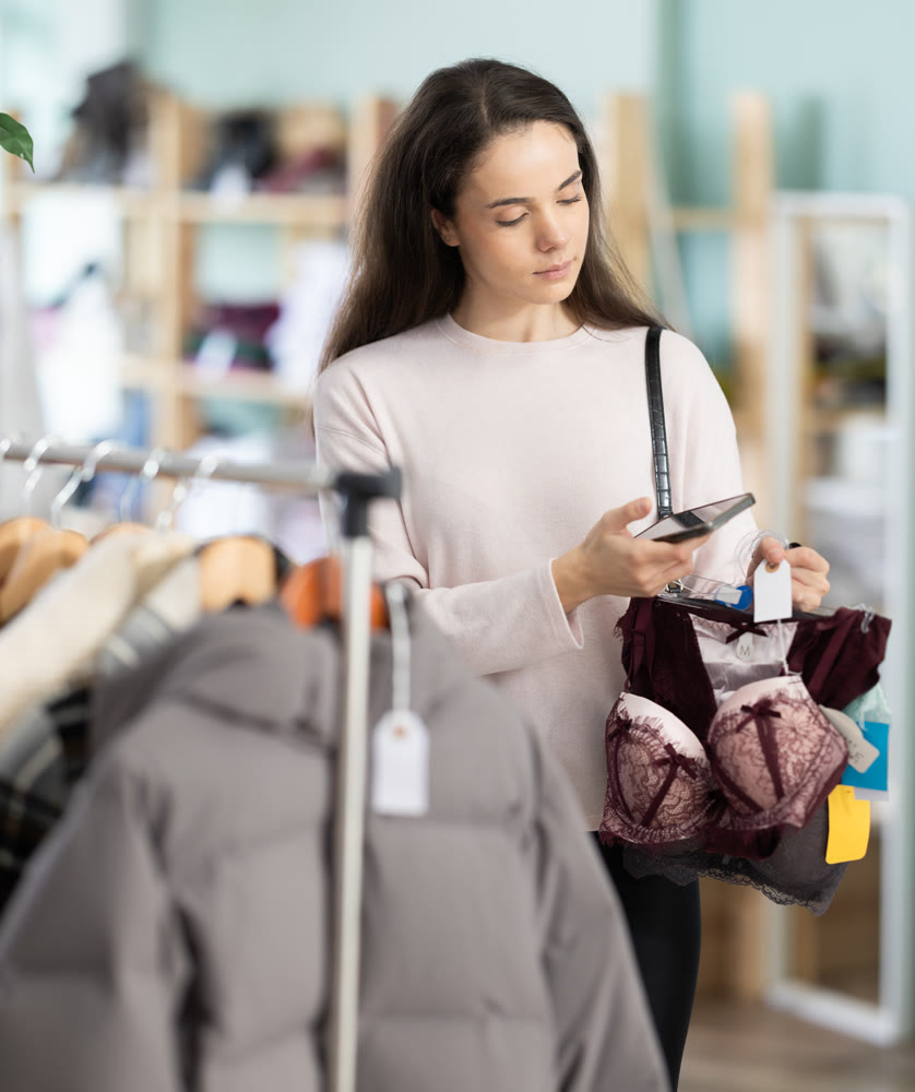 Young girl scanning QR-code on lingerie in clothing store