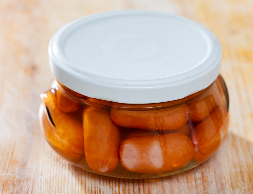 Close-up of meat sausages canned in glass jar