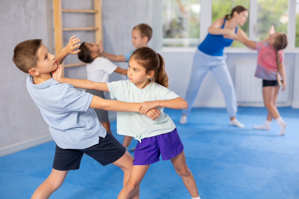 Children, boy and girl, working in pair mastering new self-defense moves at gym