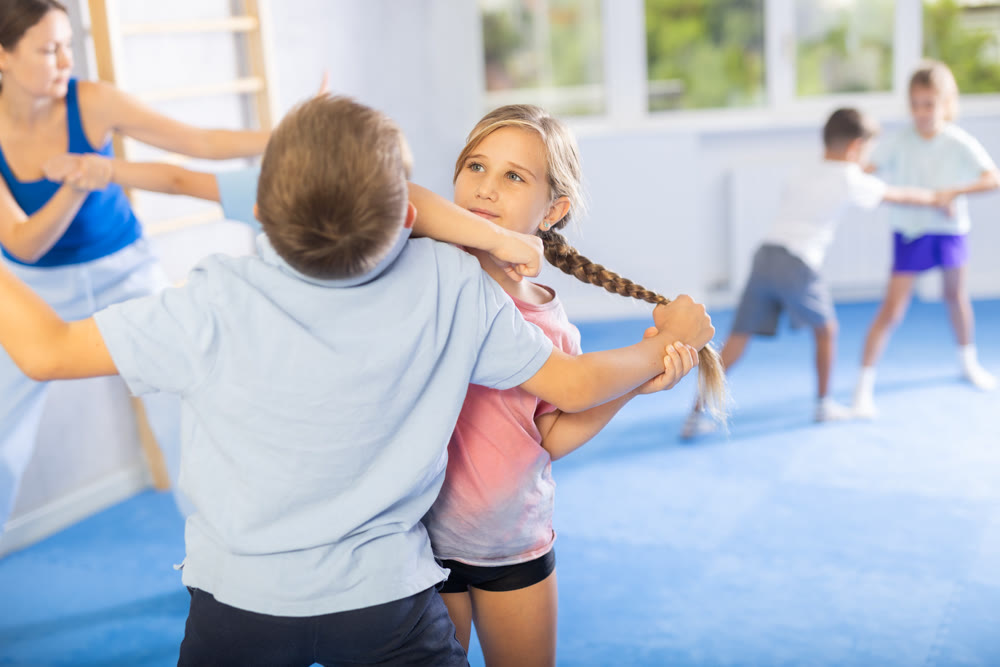 Boys and girls in gym perform basic elements of krav maga self-defense system.