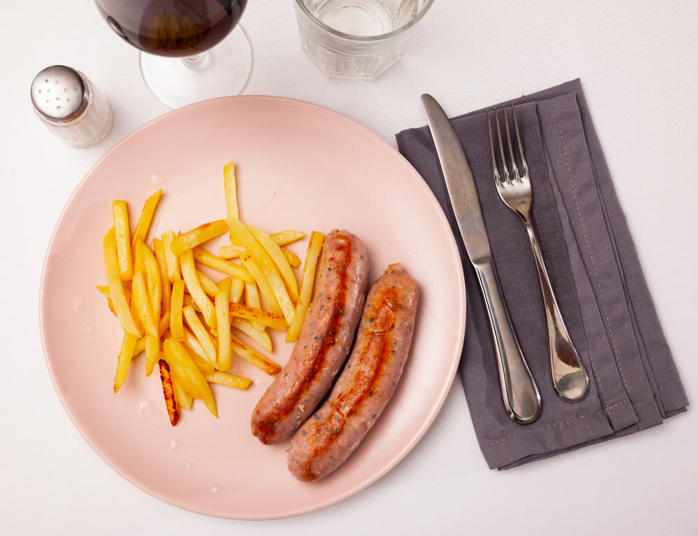 Fried meat sausages served with french fries at plate