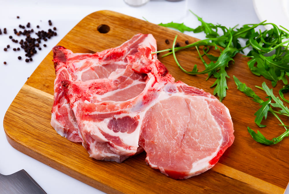 Pieces of raw pork loin with arugula and peppercorns