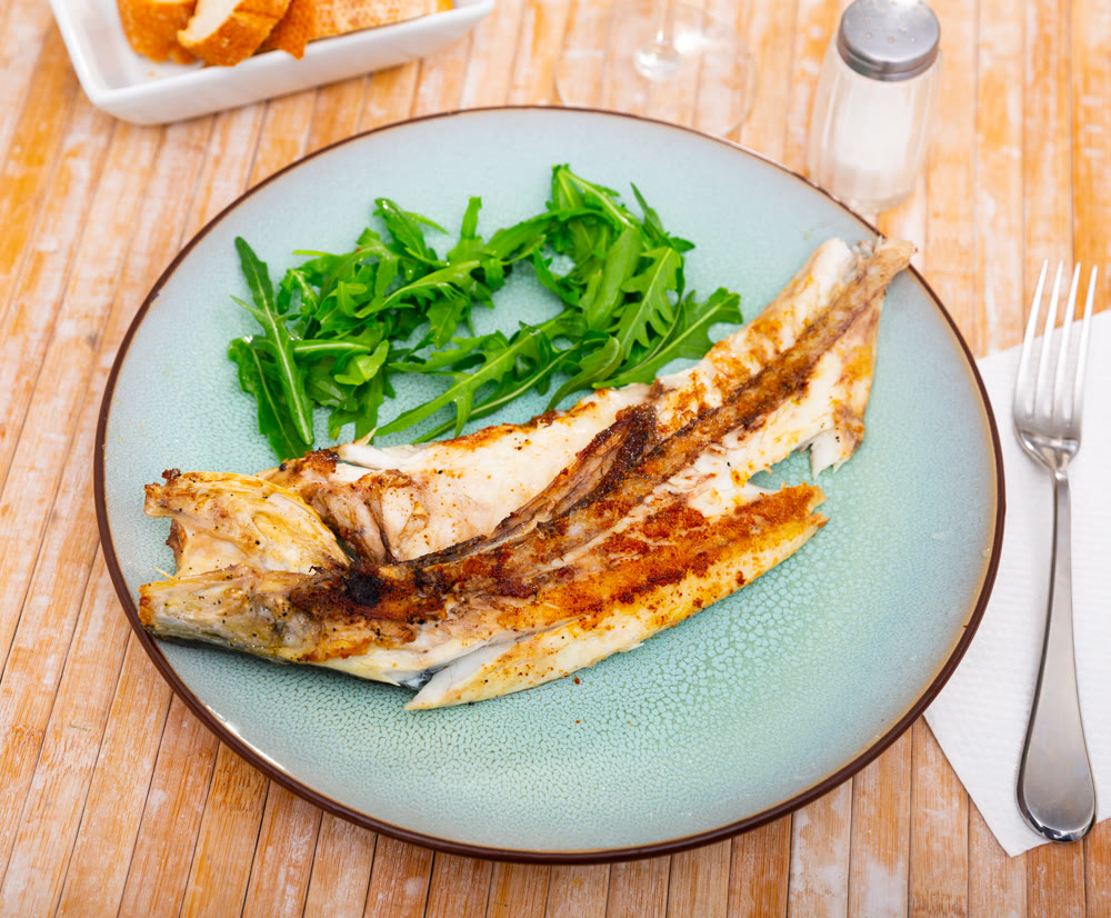 Grilled sea bass fish served with arugula