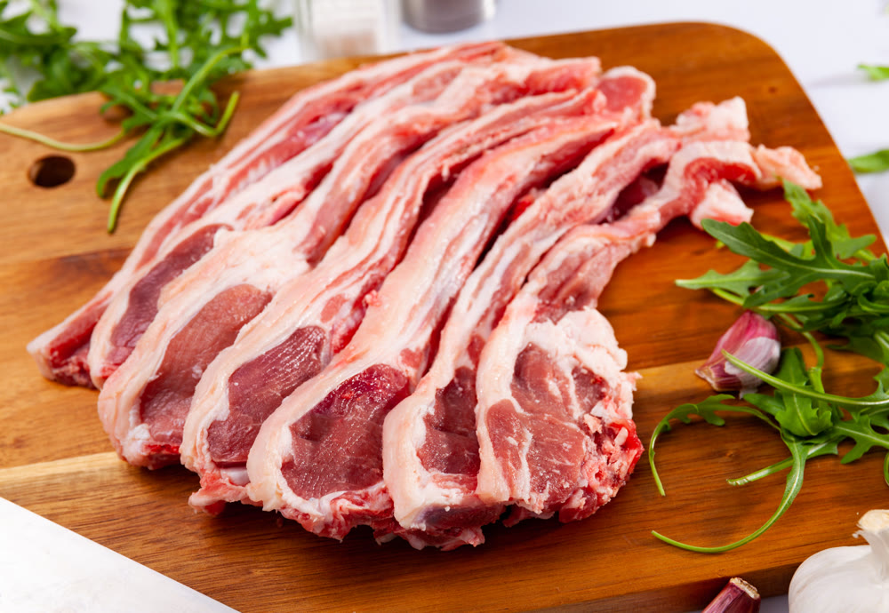Raw lamb chops on wooden cutting board