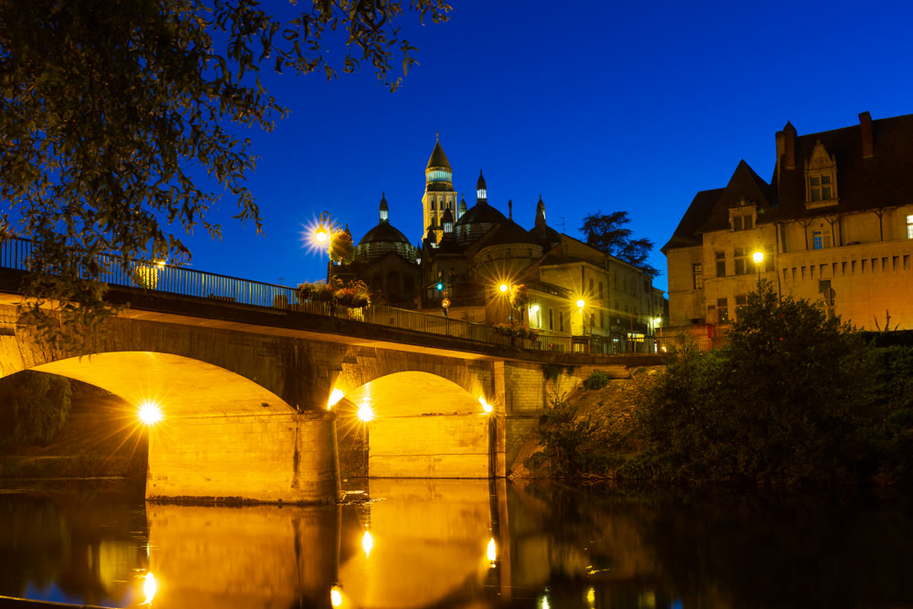 Night view of bridge over river and cathedral in Perigueux, France