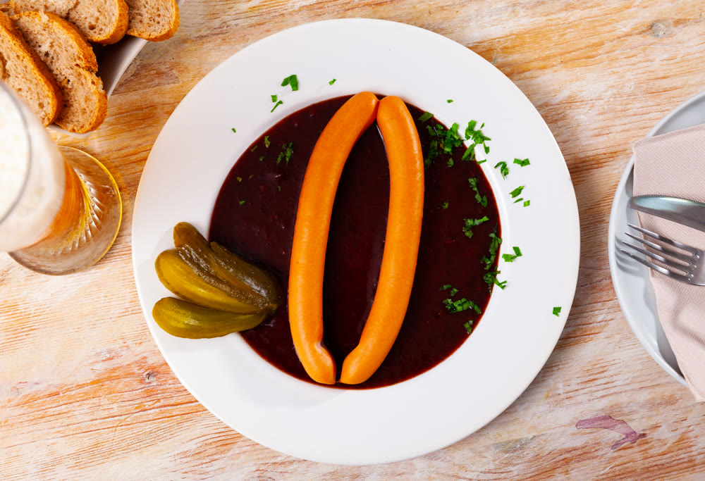 Appetizing Vienna sausages with goulash sauce on served table