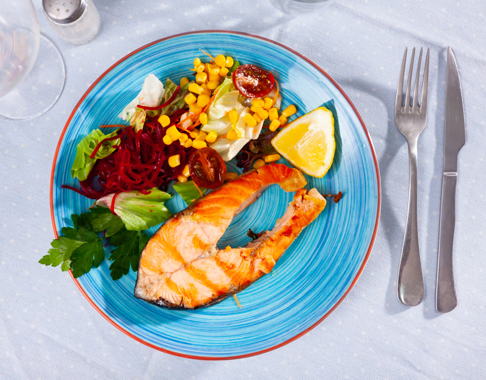 Salmon steak with salad served on plate