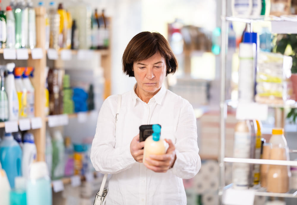 Checking expiration date of liquid hand soap - female shopper scans QR code on label of liquid hand soap using smartphone