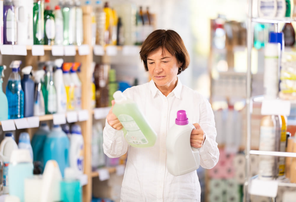 Elderly woman buyer chooses detergent in store