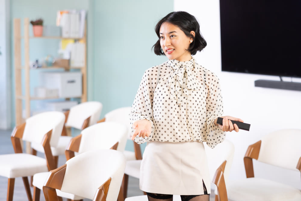 Female coach gives lecture in classroom while holding remote control