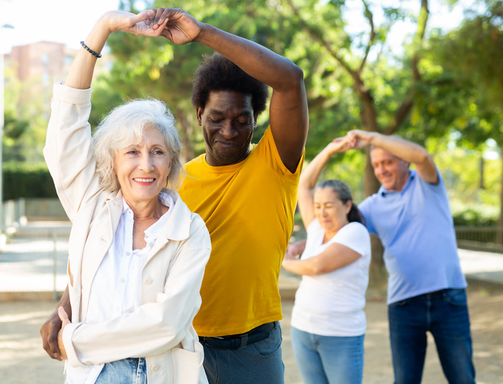 Happy positive smiling adult friends dancing pair dance in garden